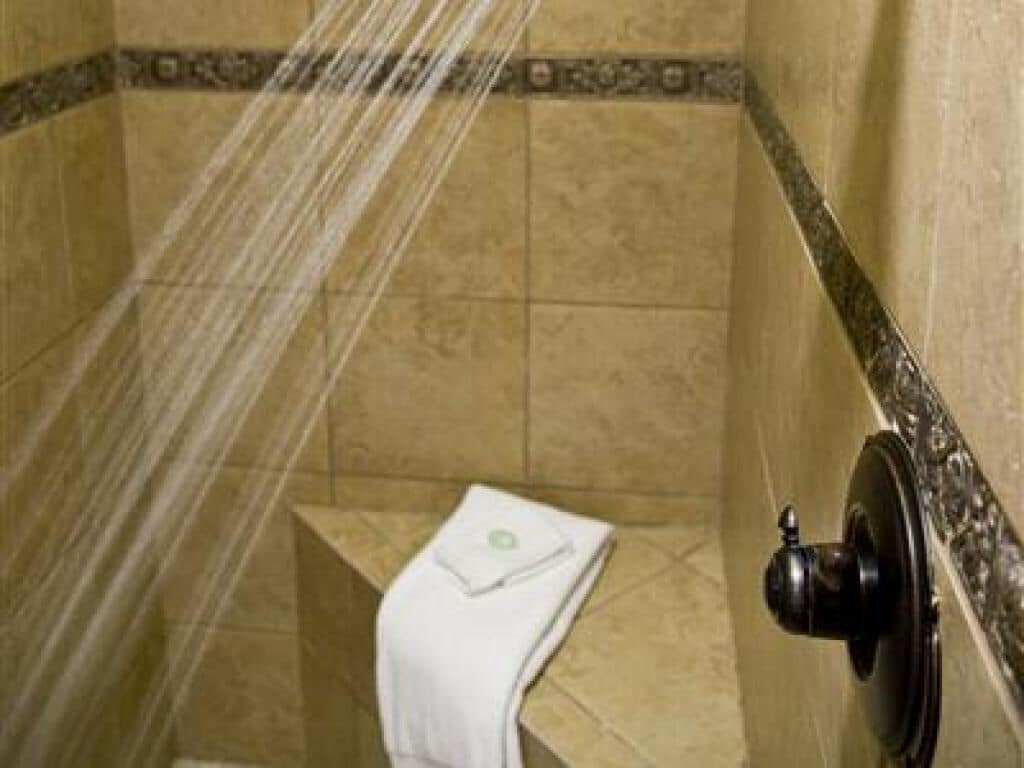 A shower with a towel hanging on the wall, a tiled floor, and a showerhead.