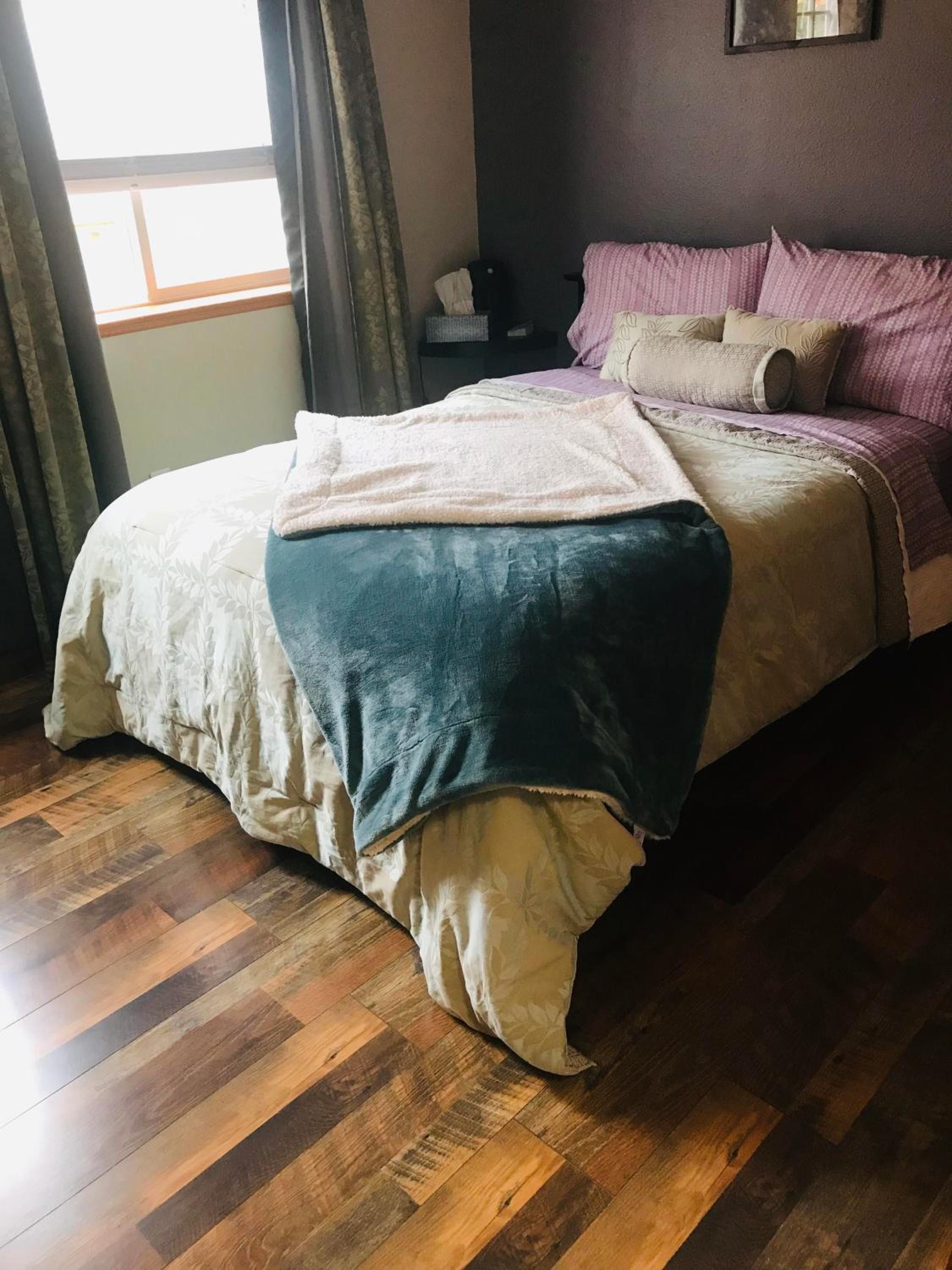 Un dormitorio con una cama, una mesita de noche y una ventana con cortinas.