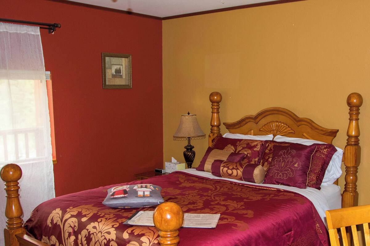 Cama bem arrumada com cabeceira de madeira, luminária de cabeceira e travesseiro decorativo.