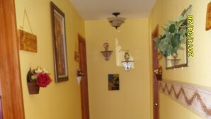A narrow hallway with yellow walls, a wooden door frame, and a carpeted floor. - A Hyde Away Inn B&B (Tok)