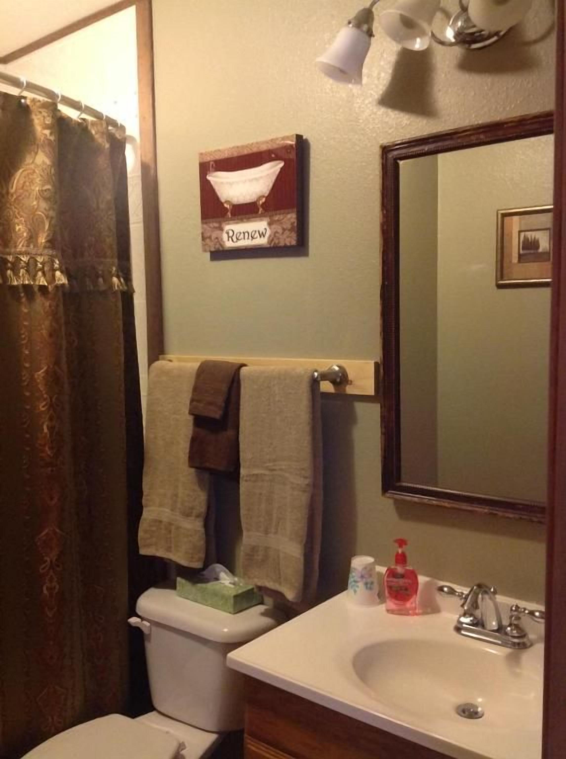 Un baño con inodoro, lavabo y toallero con dos toallas.