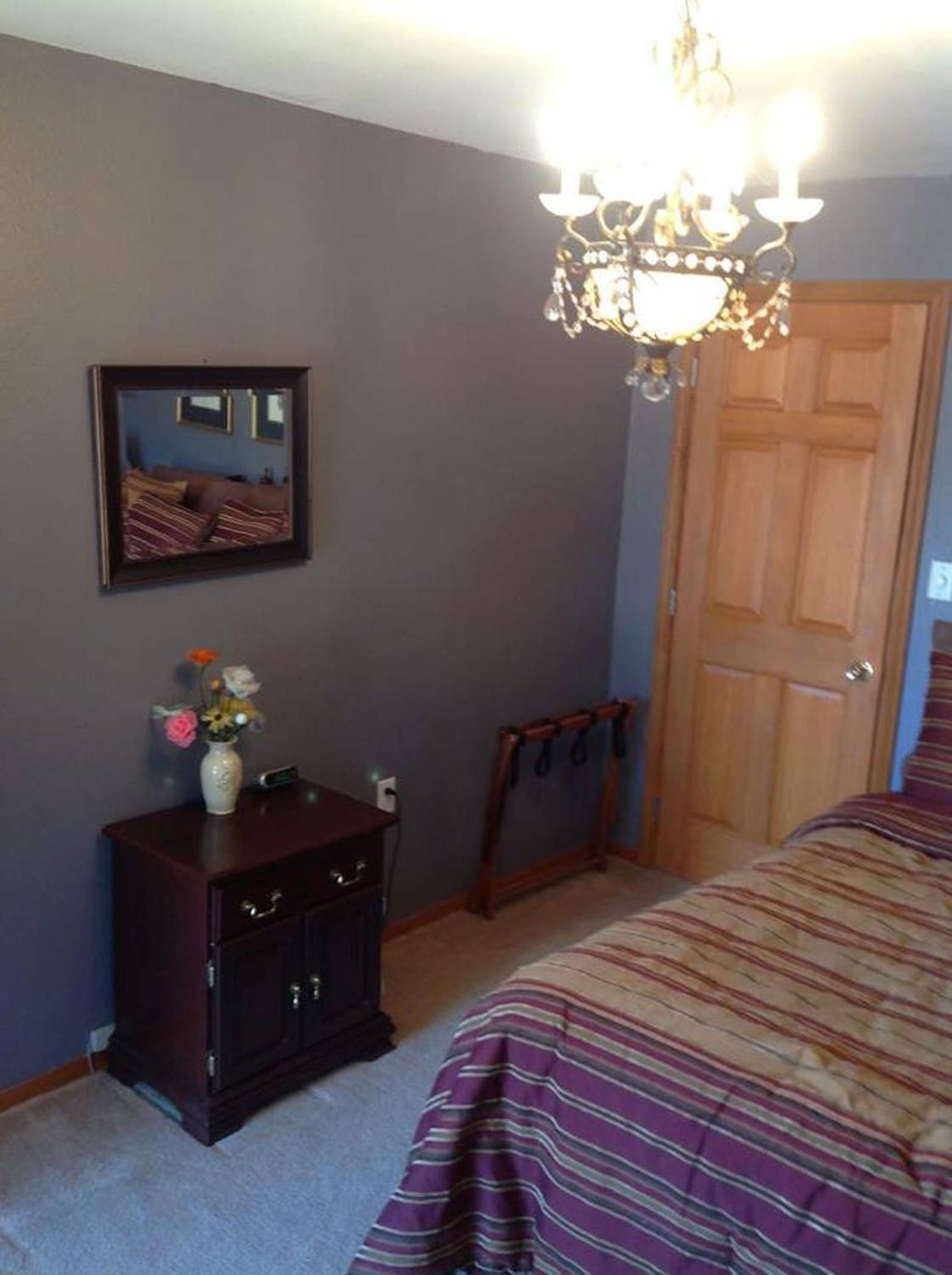 A bedroom with a bed, dresser, mirror, and chandelier.
