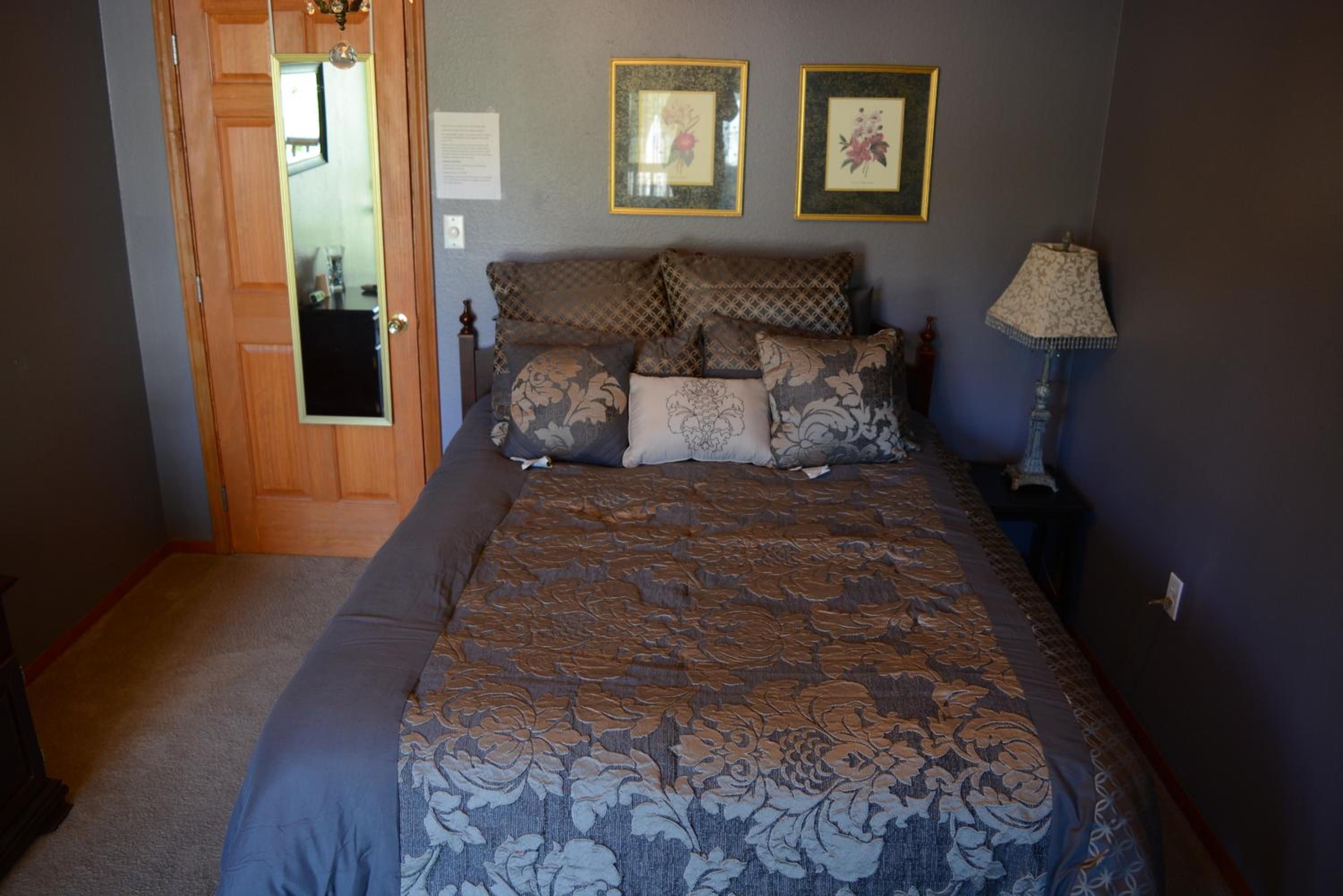 Une chambre à coucher avec un lit, une table de chevet, une lampe et une porte.