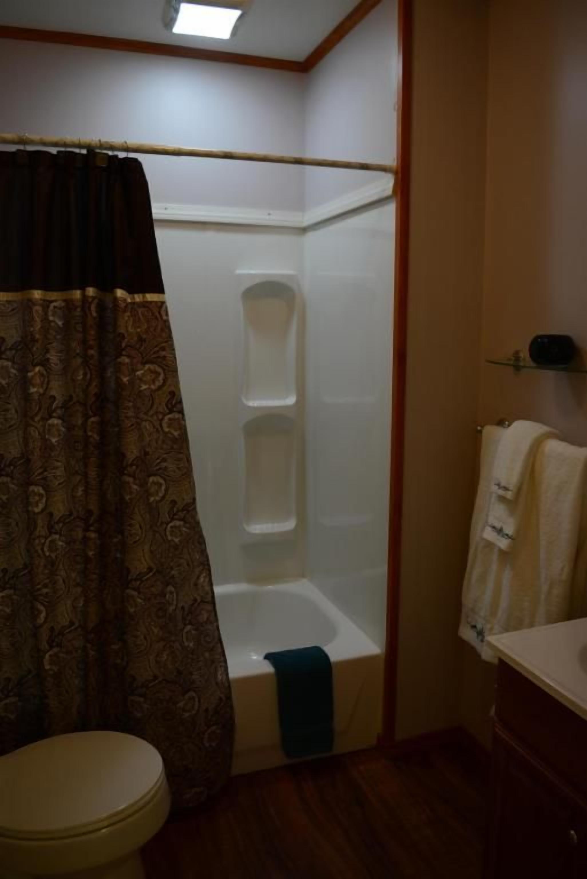 Un baño con ducha, inodoro y un perchero para toallas.