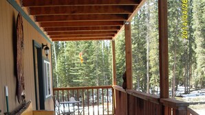 A wooden deck with a railing, a table, and chairs. - A Hyde Away Inn B&B (Tok)