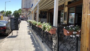 A sidewalk with a row of flower boxes and a metal railing. - Hotel Atol (Sunny Beach)