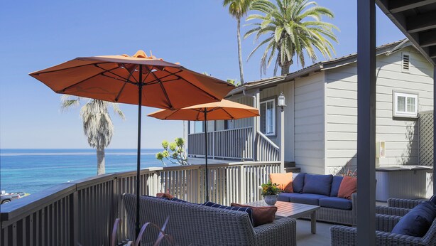 A deck with wicker furniture, a table, and an umbrella. - Scripps Inn La Jolla Cove (La Jolla)
