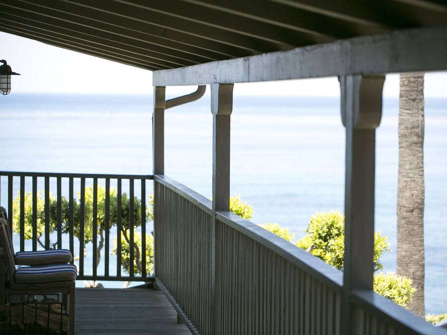 A covered outdoor area with a view of the sea, a chair, and a lamp.
