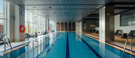 Une piscine intérieure avec des couloirs clairement délimités, une bouée de sauvetage et des chaises longues.