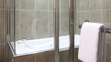 Ein modernes Badezimmer mit einer gläsernen Duschkabine, einer weißen Badewanne und einem Handtuchhalter mit einem weißen Handtuch.