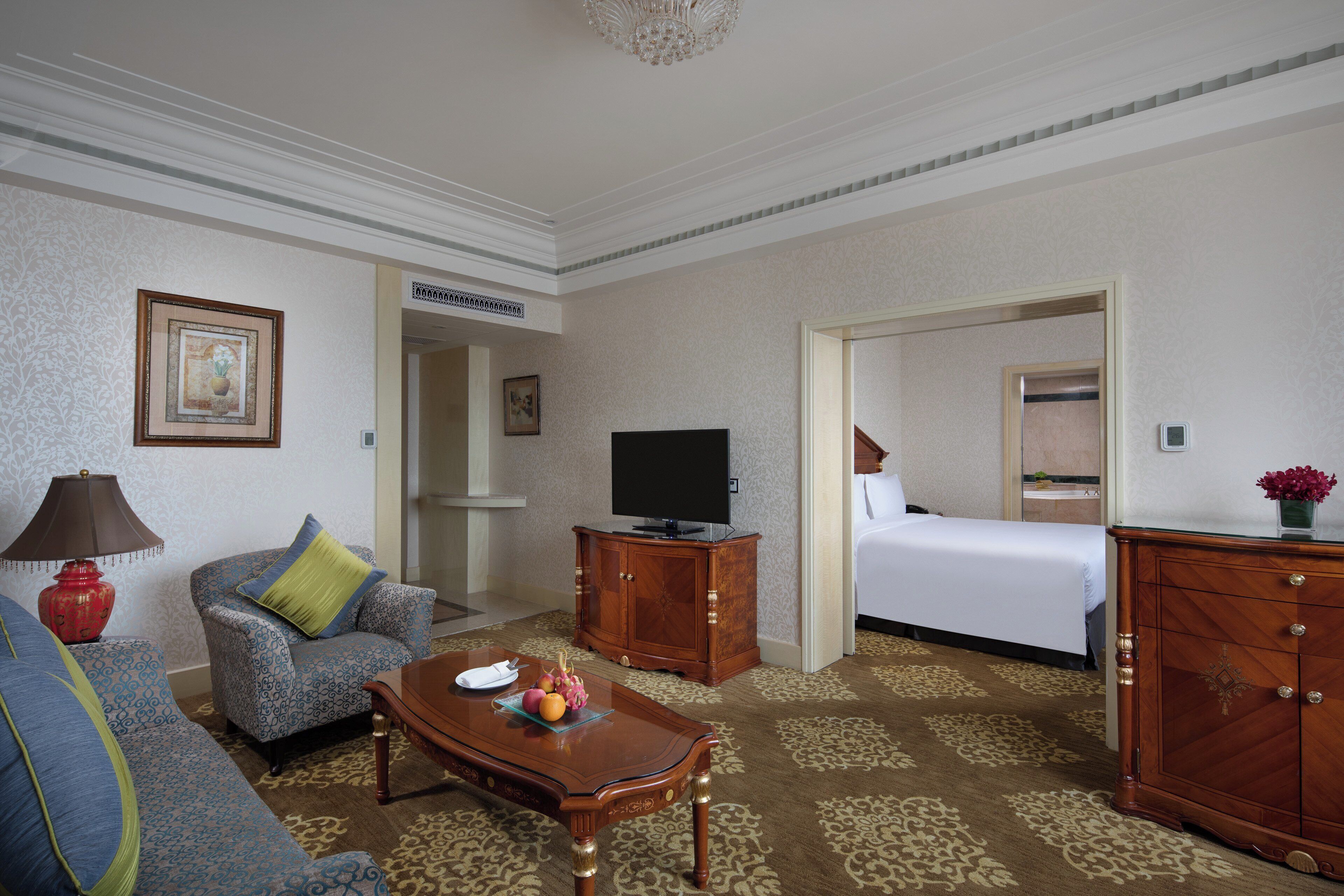 A hotel room with a sofa, a television, a wooden cabinet, and a bed.