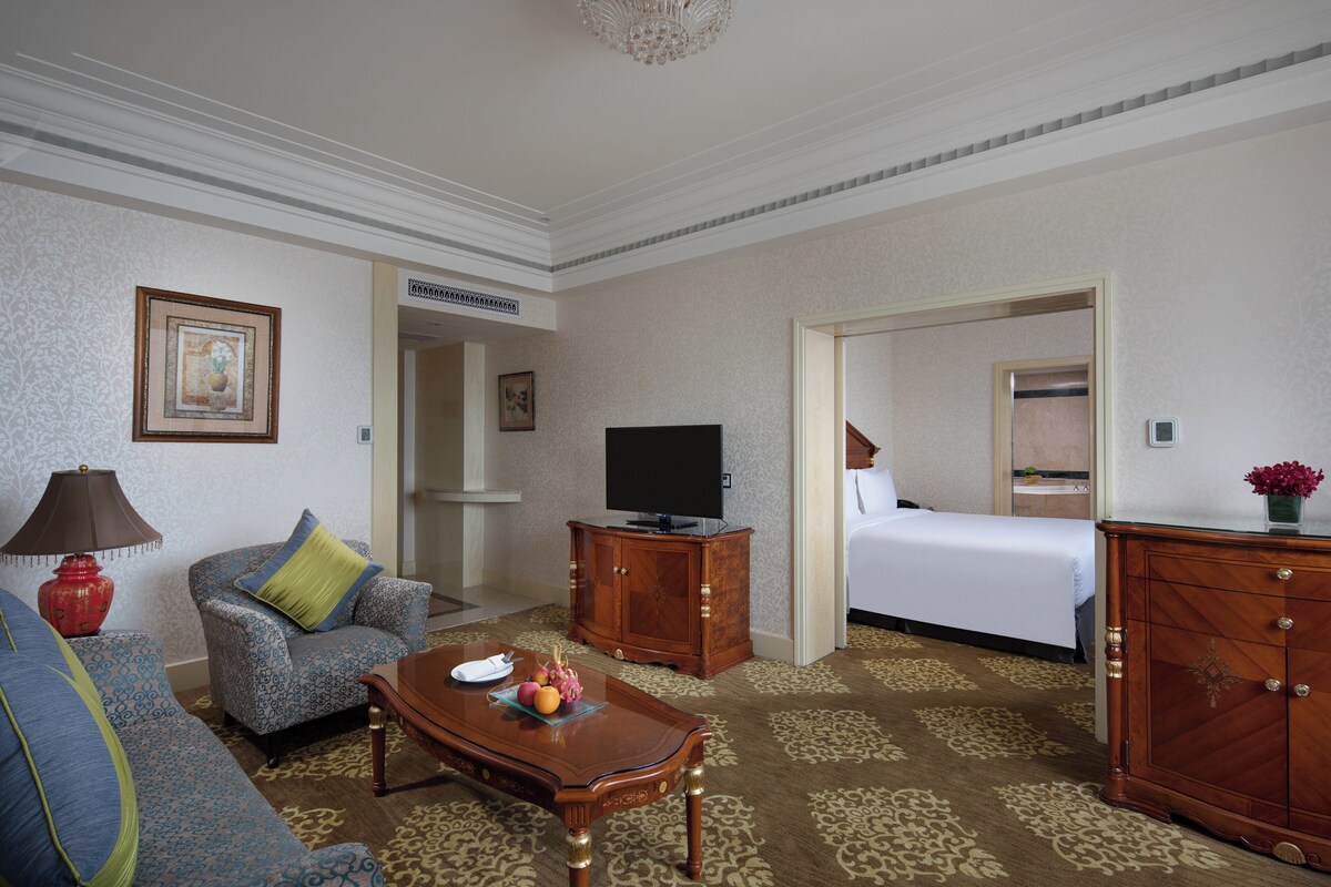 Une chambre d’hôtel avec un canapé, une table basse en bois, une télévision, un lit et une commode.
