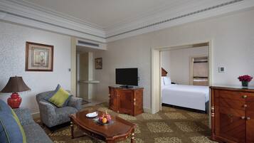 A hotel room with a sofa, a television, a wooden cabinet, and a bed.