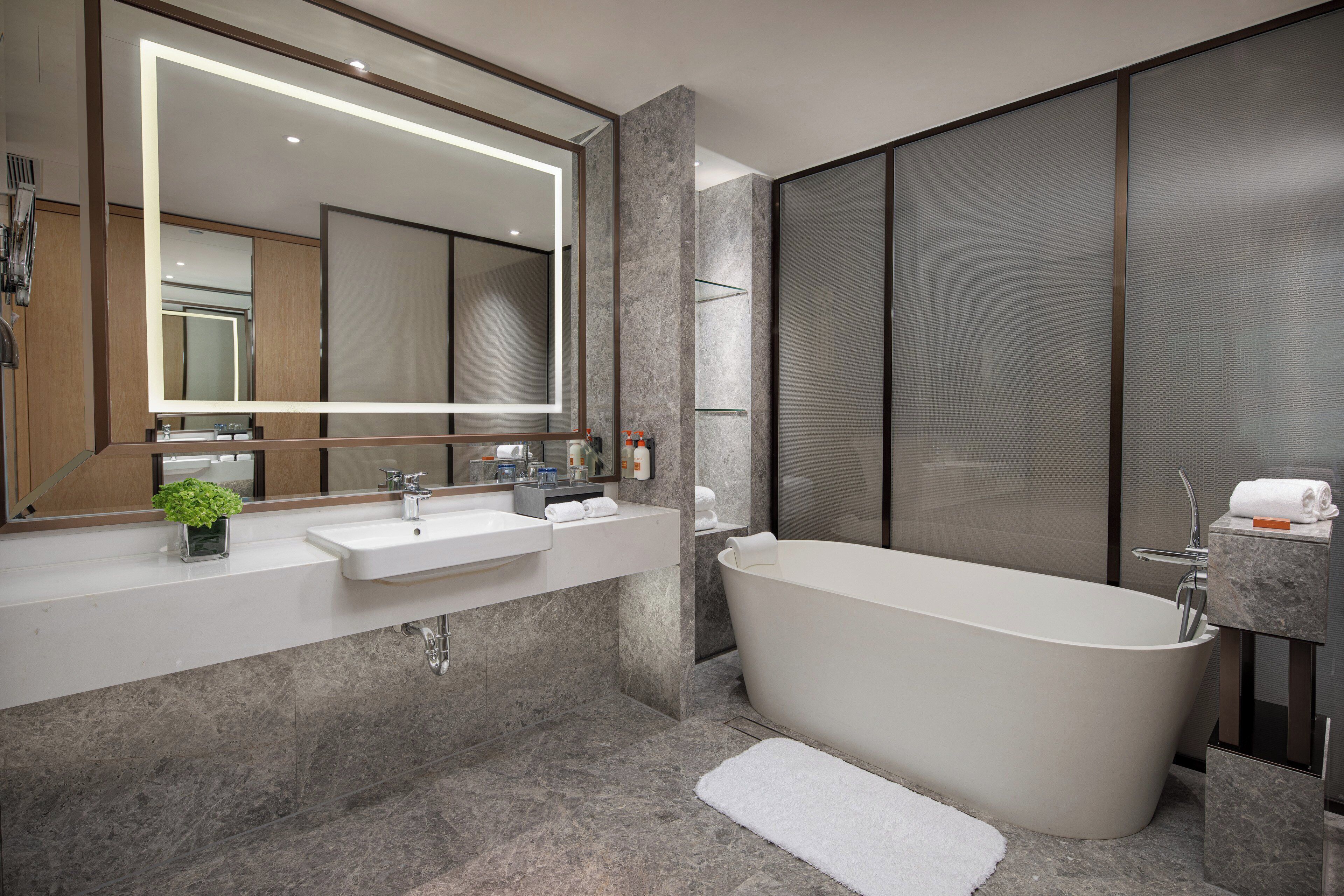 A modern bathroom with a freestanding bathtub, a large mirror, and a vanity with two sinks.