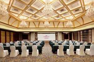 A conference room with a stage, rows of tables, and white chairs.