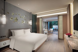 A modern hotel room with a large bed, a desk, and a view of the outdoors.