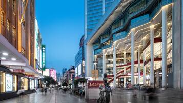 A modern urban square with a statue, high-rise buildings, and commercial establishments.