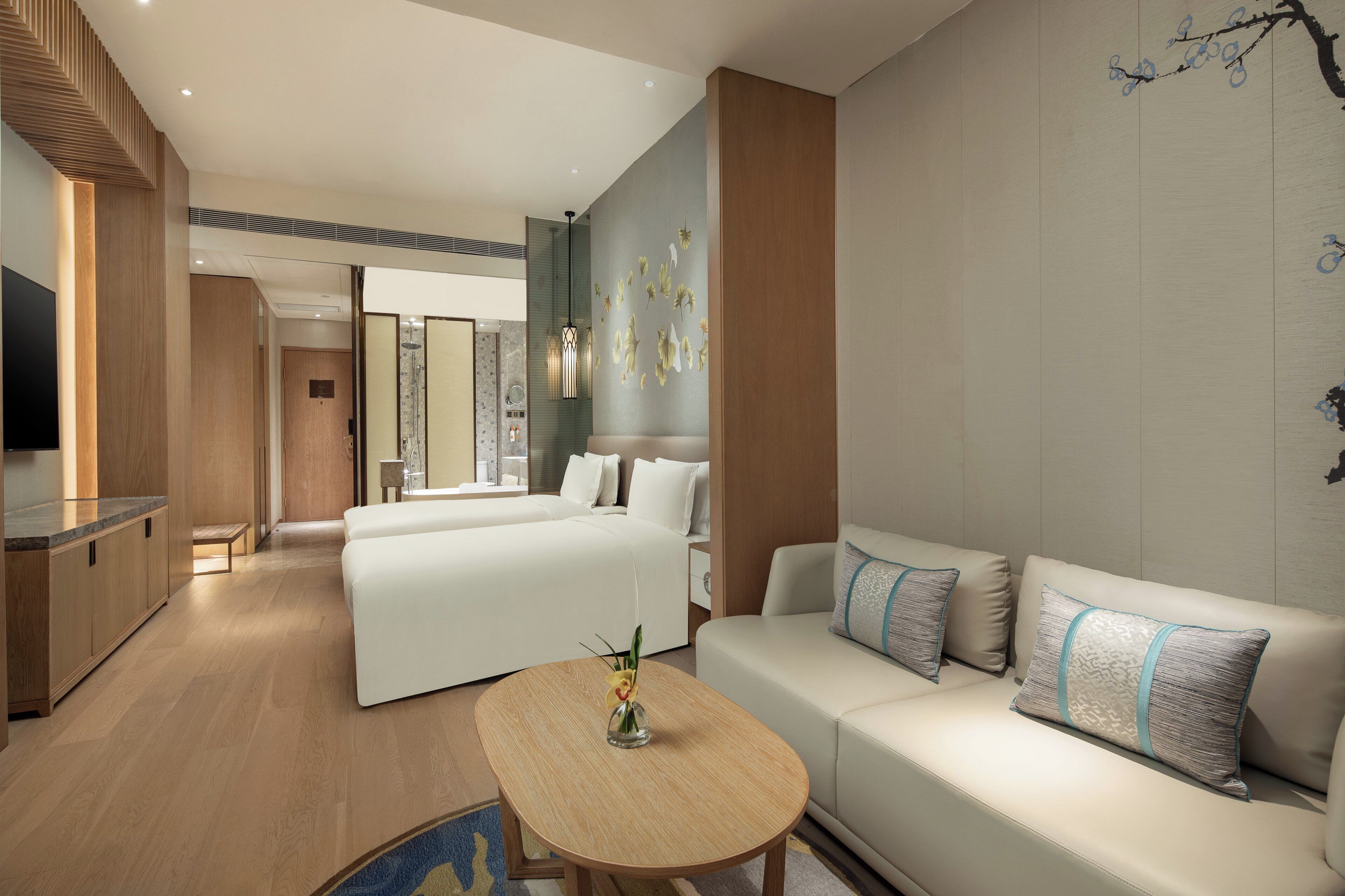 Una habitación de hotel moderna con sofá, cama, zona de comedor y televisor.