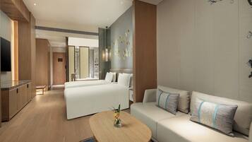 Quarto de hotel moderno com sofá, cama, área de jantar e TV.
