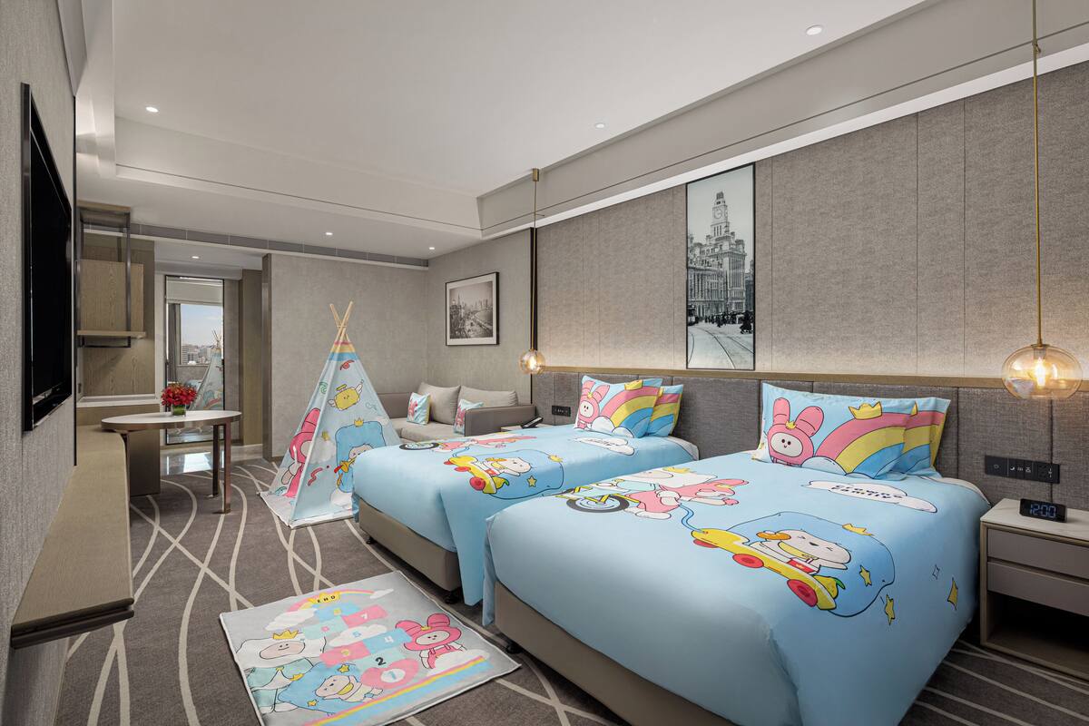 Habitación de hotel con dos camas, televisión, escritorio y vistas a la ciudad.