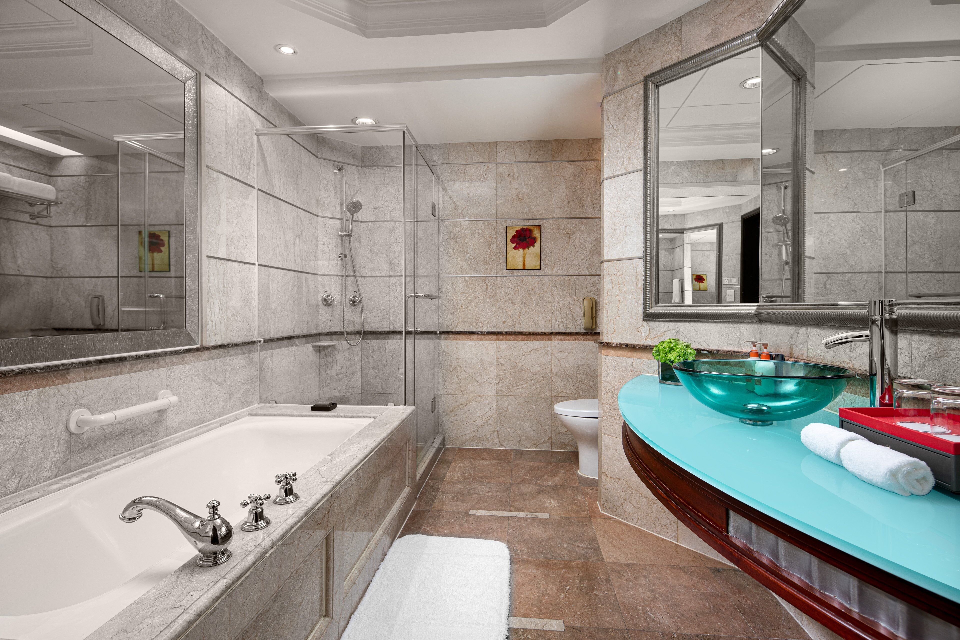 A modern bathroom with a glass-enclosed shower, a large bathtub, and a vanity with a glass bowl sink.