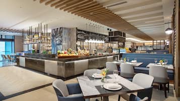Un restaurante moderno con barra central, zona de estar y cocina al fondo.