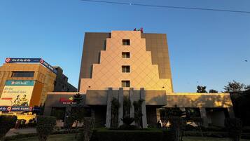 Un edificio moderno con fachada geométrica, un jardín ajardinado en primer plano y un camino pavimentado.