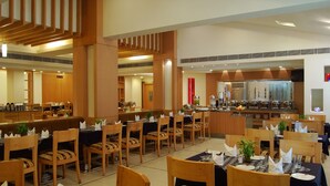 Un comedor espacioso con varias mesas y sillas, una barra central y una cocina al fondo.