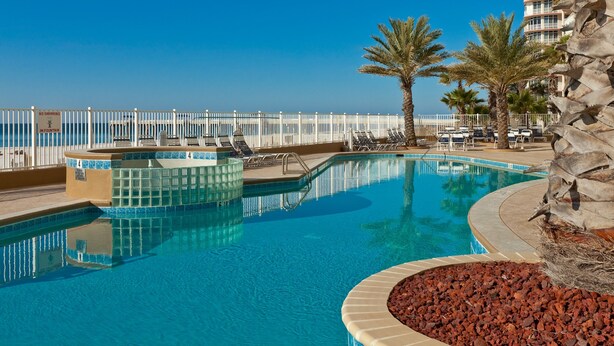 A pool area with lounge chairs, a fountain, and a view of the ocean. - Admirals Quarters by Wyndham Vacation Rentals (Orange Beach)