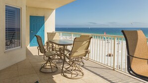 A balcony with a table and chairs, a blue door, and a view of the beach and ocean. - Admirals Quarters by Wyndham Vacation Rentals (Orange Beach)