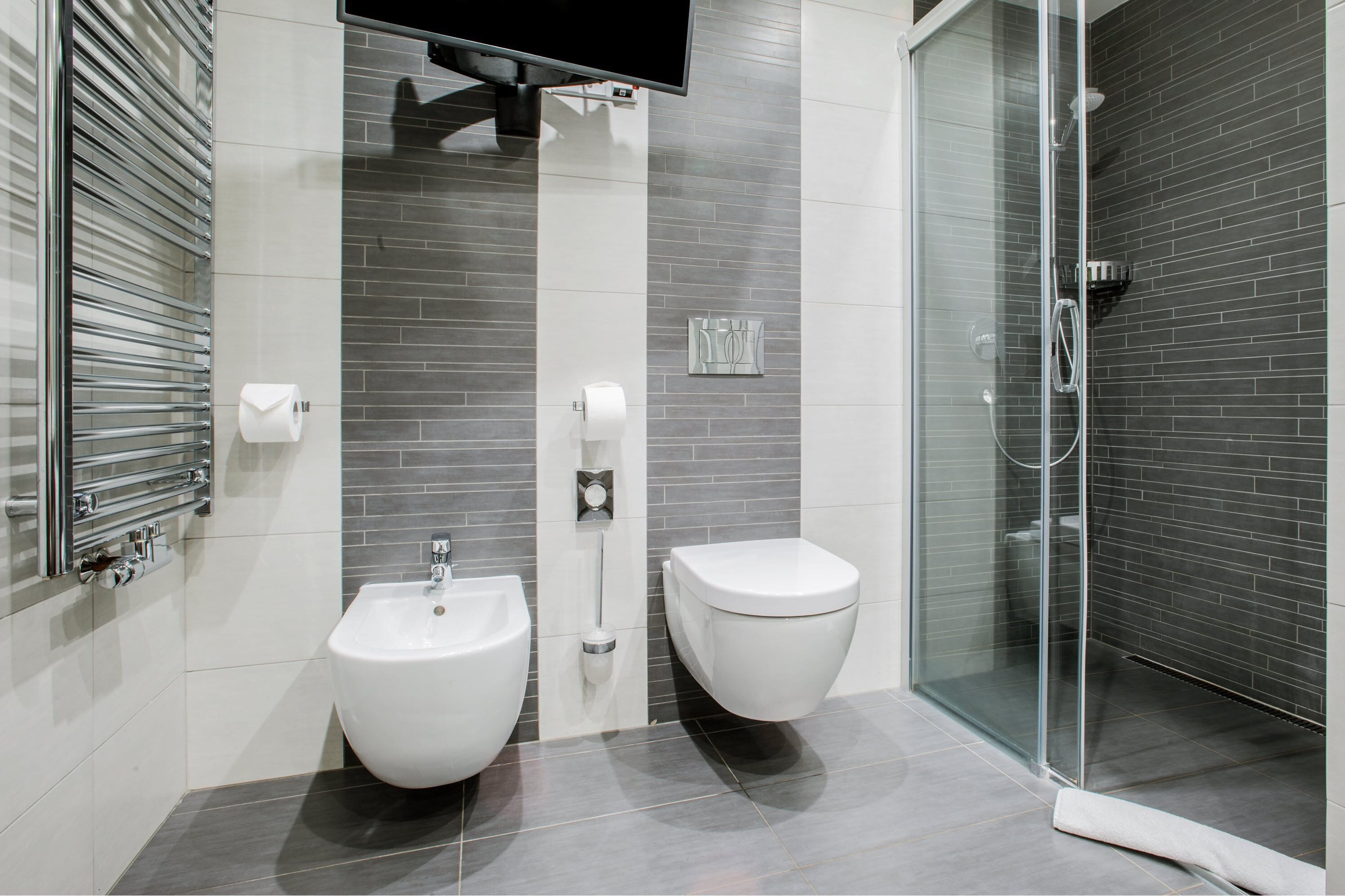 Un baño moderno con bidé, inodoro y cabina de ducha de vidrio.