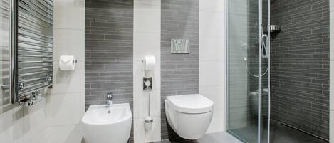 Un baño moderno con bidé, inodoro y cabina de ducha de vidrio.