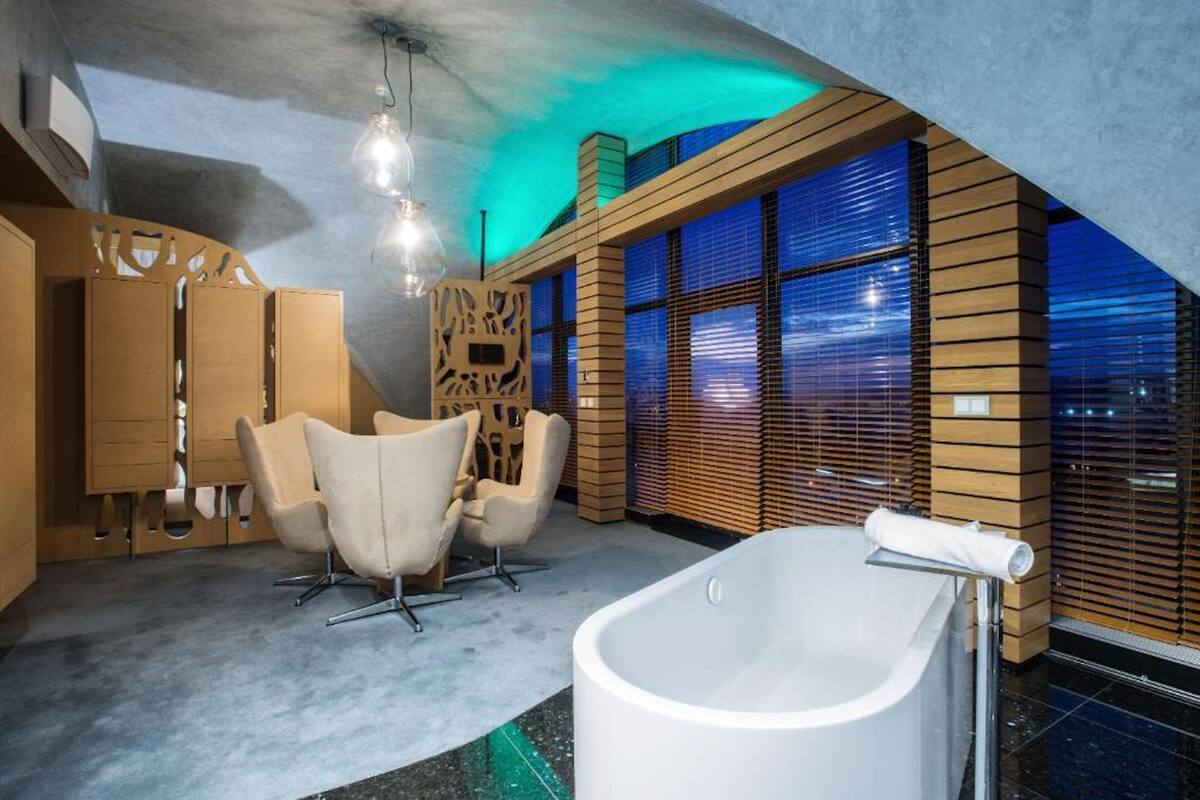 Un baño moderno con una bañera independiente, paneles de madera y ventanas amplias.