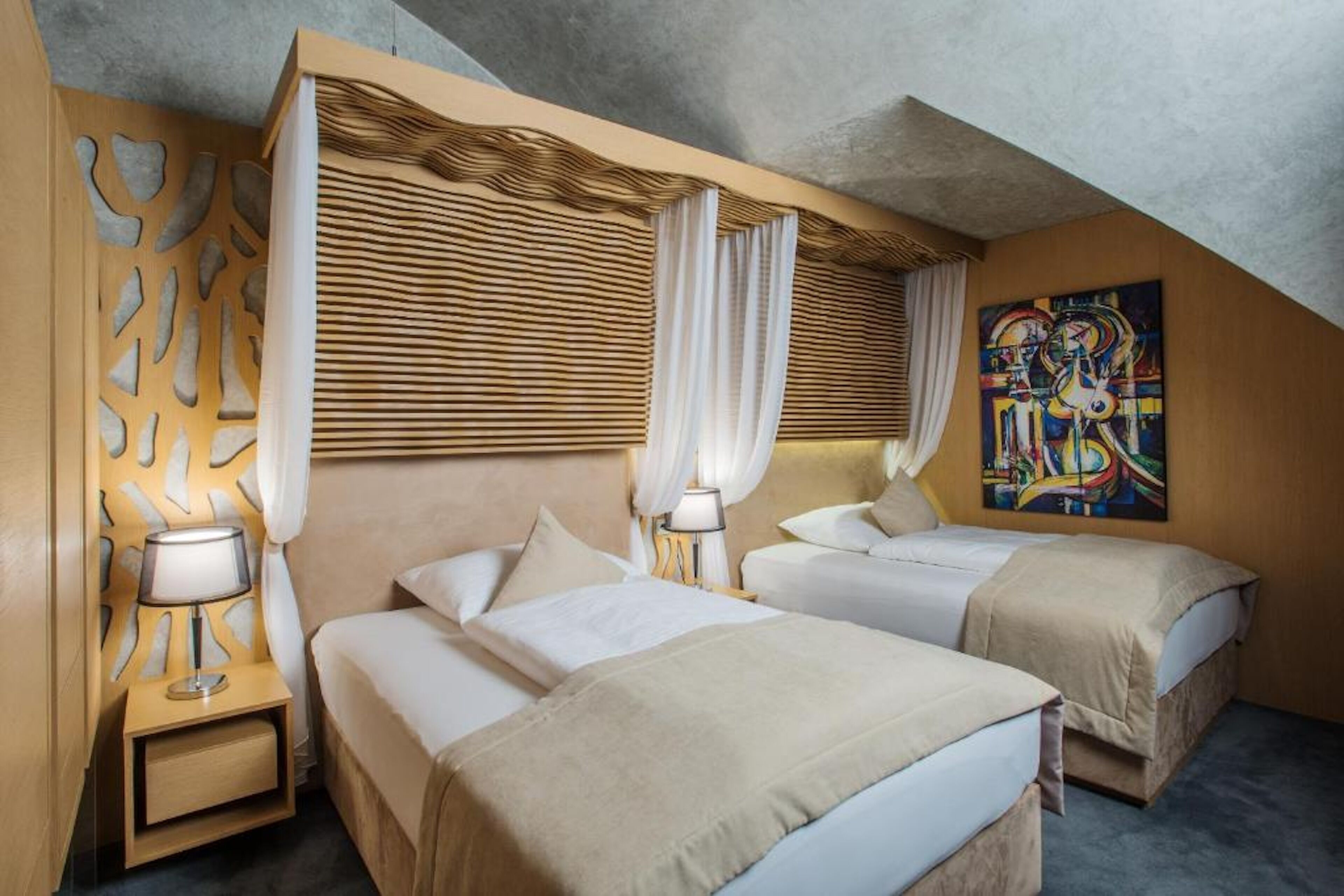 Una camera d'albergo con due letti, un grande quadro astratto e un design di soffitto originale.