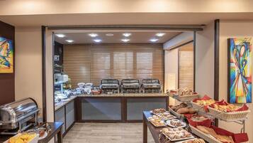 Un área de bufé con distintos alimentos, una estación de bufé y un mostrador con una máquina de café.