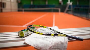 En tennisraket og en dåse tennisbolde på en bænk med et håndklæde.