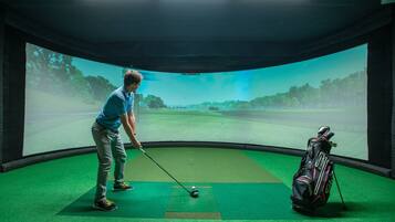 Experience golf from anywhere with our virtual golf simulator, featuring a large screen and golf equipment at the ready.