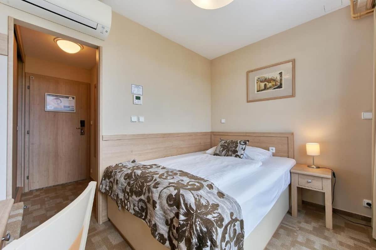 Una habitación de hotel con cama, mesita de noche e imagen colgada en la pared.