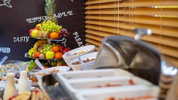 A buffet setup with various food items and a fruit display.
