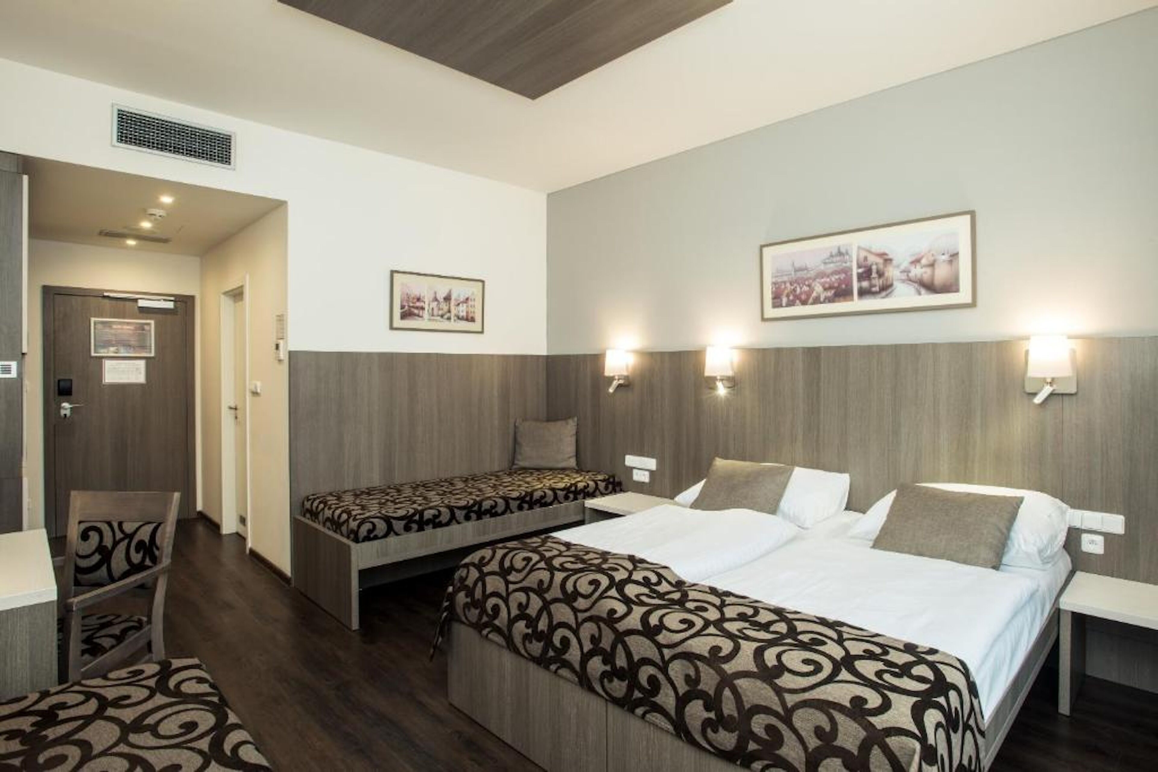 A hotel room with two beds, a desk, and a chair.