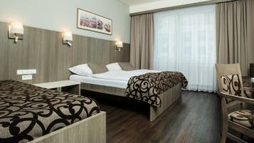 Habitación de hotel con cama, mesita de noche, una silla y una ventana con cortinas.