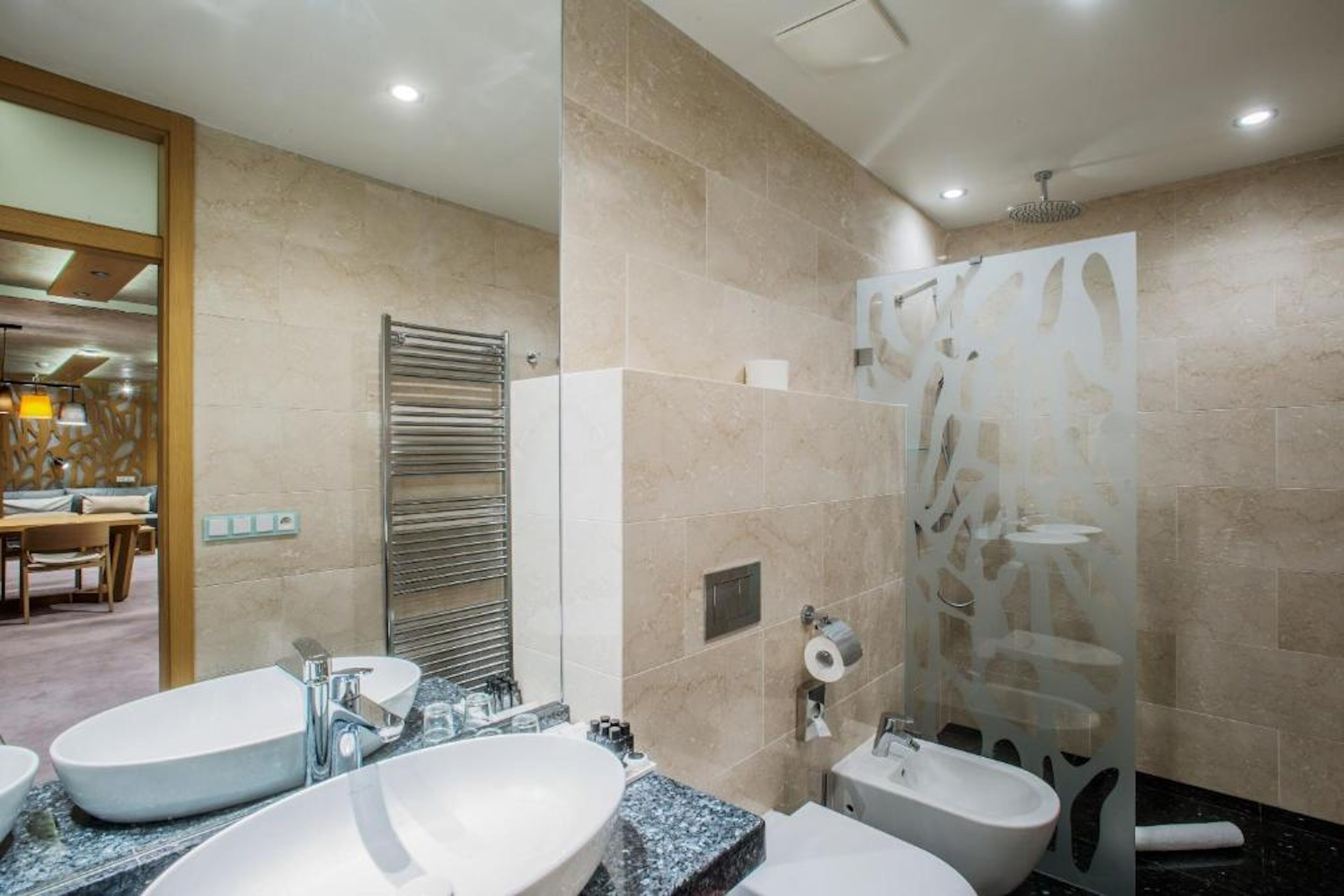 Une salle de bain moderne avec deux lavabos, un bidet et un espace douche.