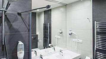A modern bathroom with a glass shower enclosure, a vanity with two sinks, and a towel rack.