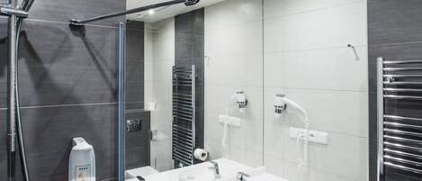 Un baño moderno con cabina de ducha de vidrio, tocador con dos lavabos y un perchero para toallas.