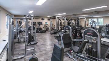 Un gimnasio equipado con diversas máquinas de ejercicio, cintas de correr y equipo para levantamiento de pesas.