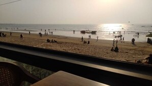 A beach scene with people, boats, and a sunset. - Citizen Hotel (Mumbai)