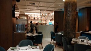 A restaurant interior with tables set for dining, a bar area with bottles, and a large pillar. - Citizen Hotel (Mumbai)