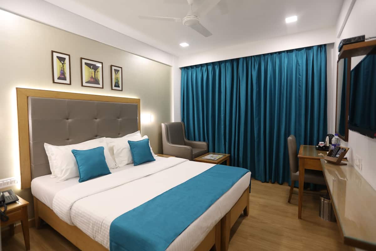 A hotel room with a bed, a chair, a desk, a phone, and a ceiling fan.