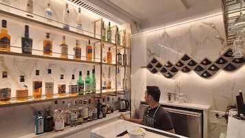 A bar area with shelves of liquor bottles, a bar counter, and a person serving.