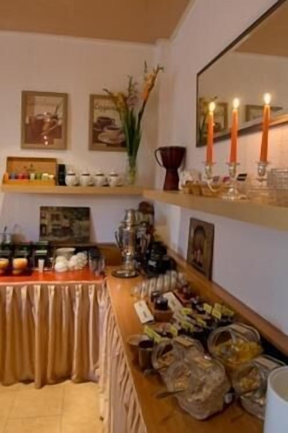 A buffet setup with various food items and condiments on a table, surrounded by shelves with decorative items and candles.